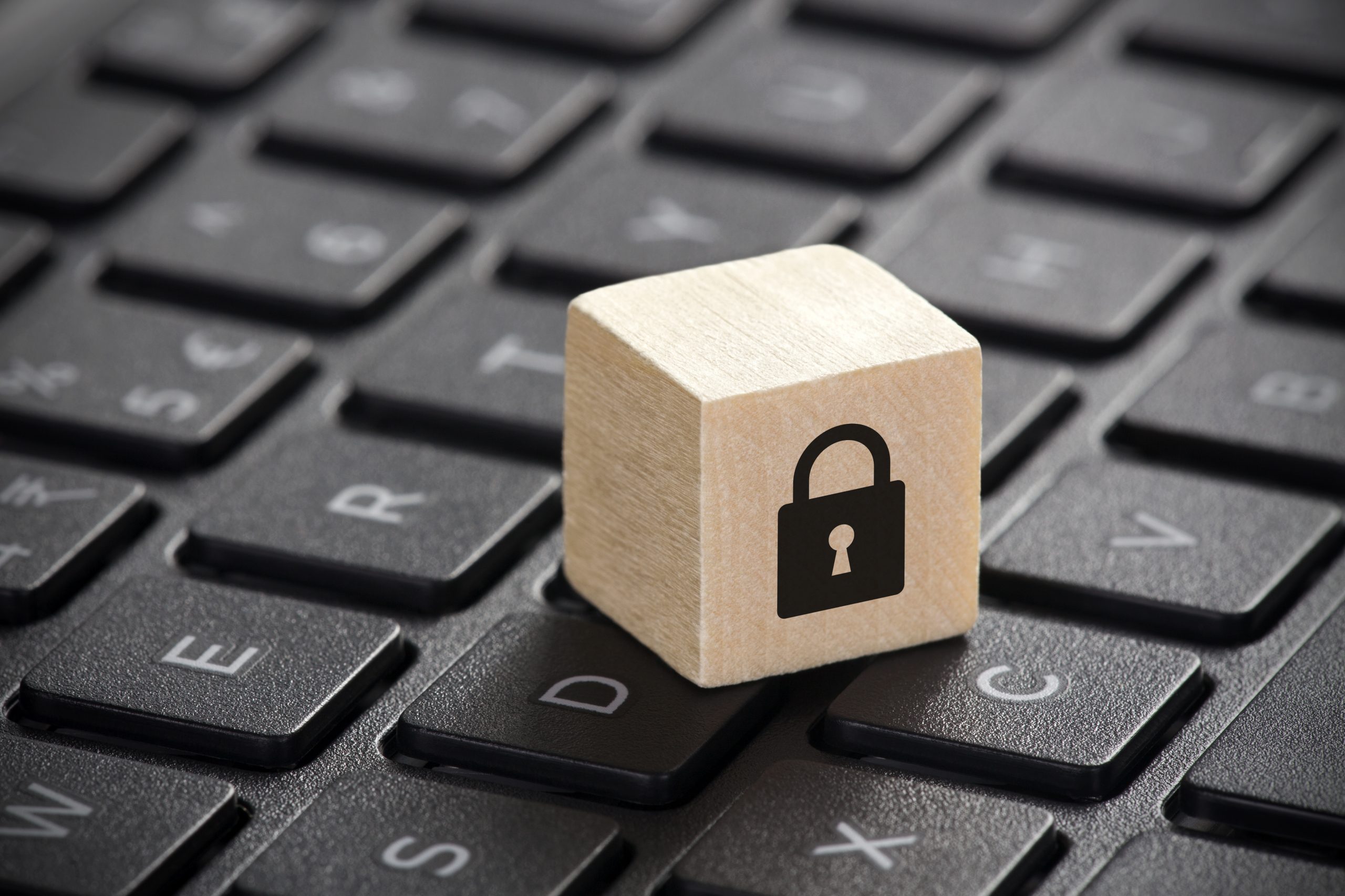 Wooden block with lock graphic on laptop keyboard. Computer secu